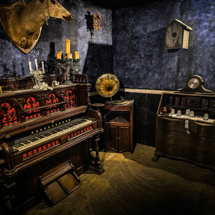 Candlelit parlor with an antique organ inside Grimwood Hall